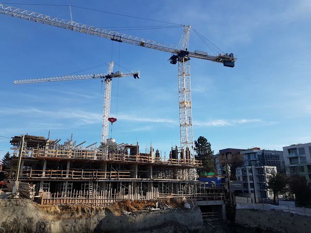 Two tower cranes over a concrete structure under construction, formwork in place across the deck