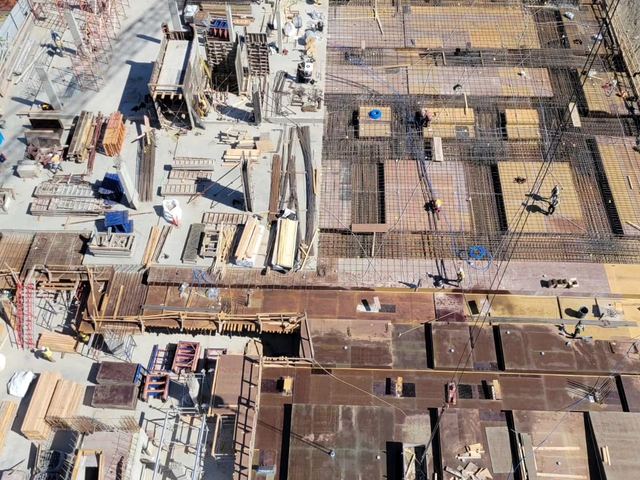 Aerial view of slab formwork, reinforcing steel, stacked materials and crews across the Langley job site
